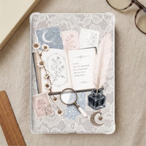Könnte beinhalten: Eine transparente Tablethülle mit einer Collage aus einem alten offenen Buch mit Blumenillustrationen, einer Feder in einem Tintenfass, einer Lupe, einem Mondsichel-Anhänger und Papierstücken mit dem Text I write not to be understood.