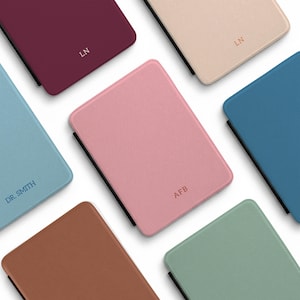 May include: A collection of rectangular, textured covers in various colors including burgundy, beige, pink, blue, brown, and sage green. Each cover features a black spine and is personalized with embossed initials or text like LN, AFB, and DR. SMITH.
