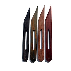 May include: Four wooden tools in varying shades of color, including black, green, brown, and red. Each tool has a long, narrow handle with a rectangular cutout and a pointed blade. The text "HONEYTOOLS" is printed on each handle.