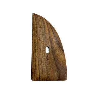 May include: A wooden pottery rib tool with a curved edge and a small hole. The tool is made of dark brown wood and has the text "HONGTOOLS" printed on the side. The tool is designed for shaping and smoothing clay.