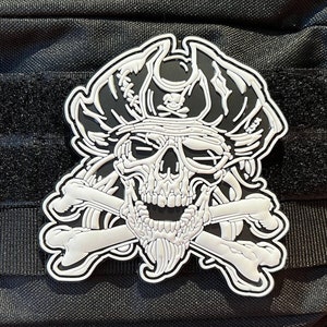 May include: White embroidered patch of a skull wearing a pirate hat with crossed bones. The skull has a beard and is wearing an eye patch.