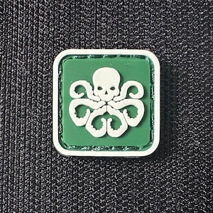 May include: A green and white embroidered patch with a skull and tentacles. The patch is square and has a white border.