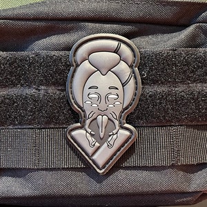 Könnte beinhalten: Schwarze taktische Tasche mit einem stilisierten grauen Aufnäher, der ein Gesicht mit langem Bart und Heiligenschein zeigt. Die Tasche hat einen Reißverschluss und Klettbänder. Die Tasche ist aus strapazierfähigem, strukturiertem Stoff.