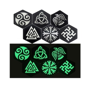 Peut inclure: Ensemble de six sous-verres hexagonaux noirs avec des motifs phosphorescents. Les motifs comprennent un triskèle, un nœud, un corbeau, une croix solaire et une swastika. Les sous-verres sont présentés dans leurs états normal et lumineux.