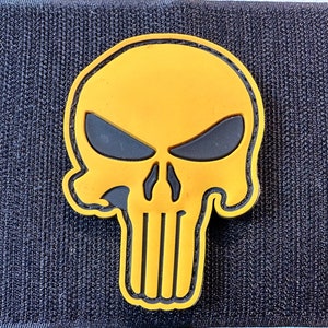 May include: Yellow skull patch with black eyes and a black outline. The skull has a black stripe down the centre.