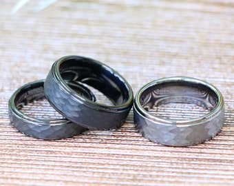 May include: Three black tungsten carbide rings with a hammered finish. The rings are stacked on top of each other.