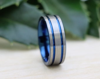 May include: A blue and silver tungsten carbide ring with two silver bands.