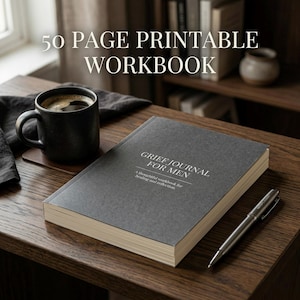 May include: A dark gray workbook titled "GRIEF JOURNAL FOR MEN" with the text "50 PAGE PRINTABLE WORKBOOK" above it. A black mug of coffee and a silver pen rest on a wooden surface.