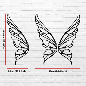 K&ouml;nnte beinhalten: Schwarze Metall-Schmetterlingsfl&uuml;gel, 60 cm hoch und 52 cm breit. Die Fl&uuml;gel werden vor einer wei&szlig;en Backsteinmauer pr&auml;sentiert. Die Fl&uuml;gel sind ein dekorativer Artikel. Die Fl&uuml;gel sind 23,6 Zoll hoch und 20,4 Zoll breit.