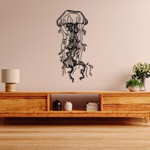 May include: Black metal wall art sculpture of a jellyfish with flowing tentacles and leaves. The sculpture is mounted on a light beige wall above a wooden entertainment center.