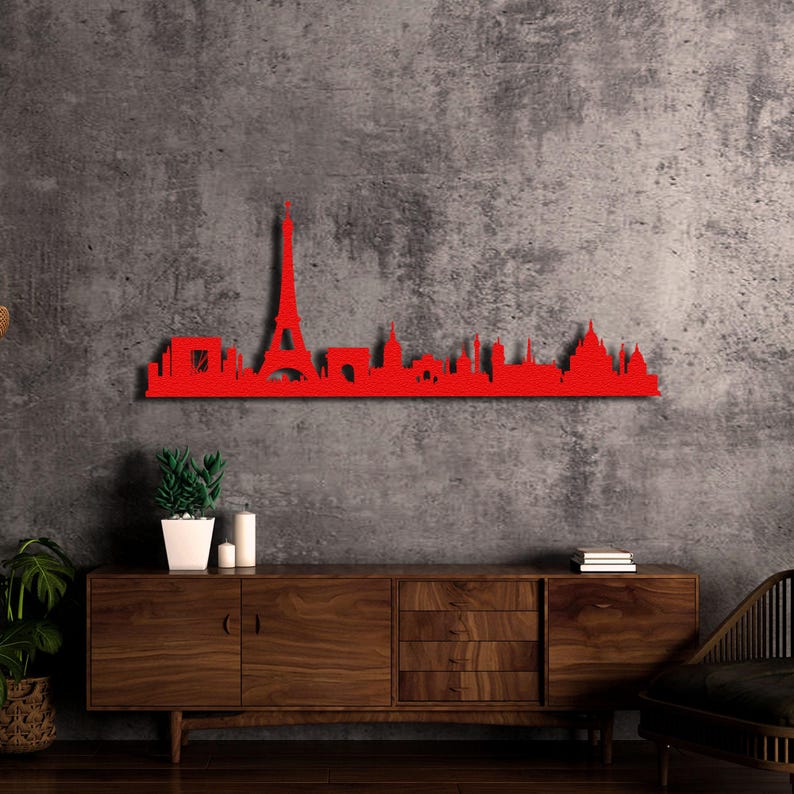 May include: Red metal Paris skyline wall art featuring the Eiffel Tower and other iconic landmarks. The art is mounted on a wall above a wooden dresser.