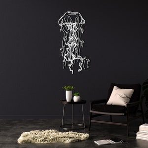 May include: A white outline of a jellyfish with vines hanging from it on a black wall. A black chair with a white pillow sits in front of a small table with two potted plants.