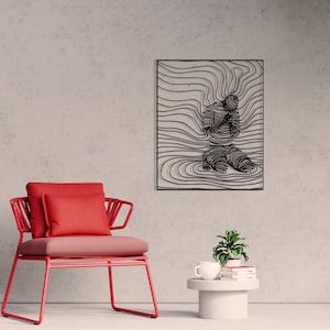 Op de afbeelding: Zwarte metalen wandkunst met een gestileerde figuur in een knielende houding, omringd door abstracte lijnen. De kunst is ingelijst en hangt aan een lichtgrijze muur.