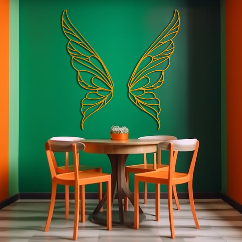 K&ouml;nnte beinhalten: Esszimmer mit gr&uuml;ner Wand und goldener Schmetterlingsfl&uuml;gel-Wandkunst. Ein runder Holztisch mit orangefarbenen St&uuml;hlen und eine kleine Pflanze in einem orangefarbenen Topf. Der Raum hat eine orangefarbene Akzentwand.