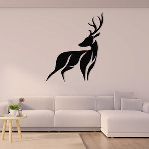 May include: Black silhouette of a deer with antlers, mounted on a white wall above a white couch. The deer is facing the right side of the image.
