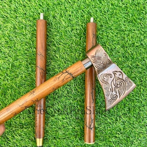 May include: Three wooden walking sticks with a decorative axe head. The axe head is made of metal and has a detailed design. The sticks are brown with a crackled finish.