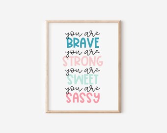 以下が含まれることがあります： 「You are brave, you are strong, you are sweet, you are sassy」というテキストがカラフルな文字で書かれた額装されたプリントです。
