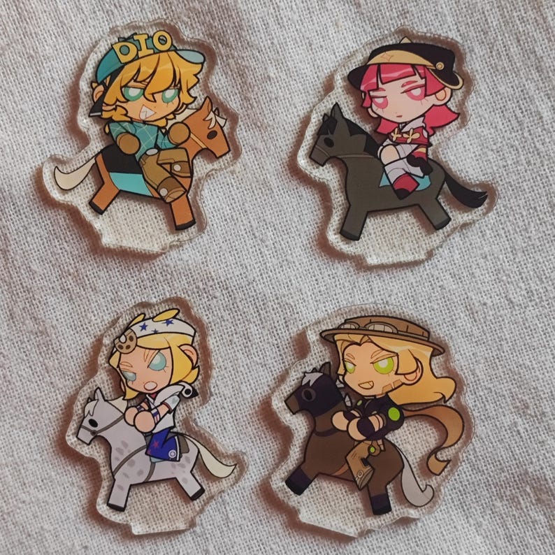 May include: Four clear acrylic charms depicting cartoon characters on horses. Each charm showcases a distinct character design with varied outfits and hair colours. The charms are set against a light-coloured fabric backdrop.