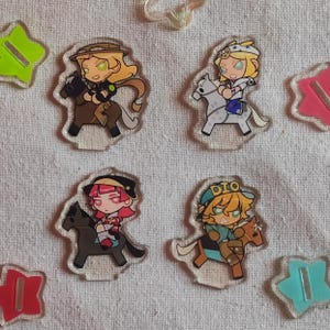 May include: Four acrylic standees depicting anime-style characters on horseback. Each character has distinct hair and attire. The standees are on a white surface, with colourful star-shaped and rectangular accents.