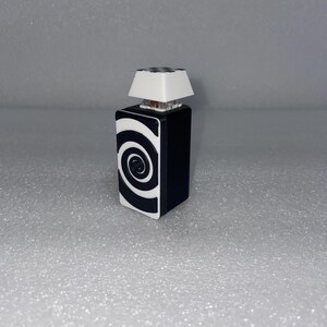 Può includere: Una lampada con un motivo bianco e nero e un paralume bianco. La lampada ha un motivo circolare sulla base.
