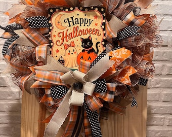 May include: A decorative Halloween wreath featuring orange, black, and tan mesh ribbons with a central sign that reads Happy Halloween, depicting a ghost, a black cat, and a pumpkin. The wreath is accented with patterned ribbons and bows.