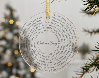 May include: Clear, circular Christmas ornament with gold trim and a gold ribbon for hanging. The ornament features the text "Custom Song" in the center, surrounded by song lyrics. A personalized holiday decoration.