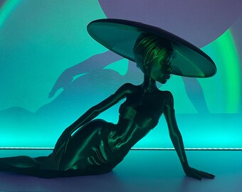 May include: A black figurine of a person wearing a large, wide-brimmed hat. The figurine is posed in a reclining position with one arm extended and the other resting on the floor. The background is a gradient of blue and green.
