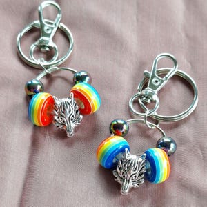 May include: Two silver keychains with rainbow colored beads and silver wolf charms.