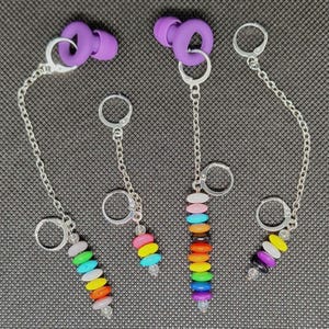 May include: A set of five rainbow-colored beaded earrings with silver hoops and chains. Each earring features a different color combination of beads, including red, orange, yellow, green, blue, indigo, and violet.