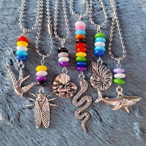 May include: Seven silver necklaces with colorful bead charms and silver animal pendants. The pendants include a frog, a snake, a cicada, a swallow, a nautilus shell, and a shark.