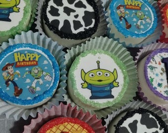 May include: A collection of nine decorated round cookies featuring various Toy Story characters and designs. The cookies are arranged in a circle and decorated with sprinkles and edible images. The designs include Woody, Buzz Lightyear, Alien, and a cow pattern.