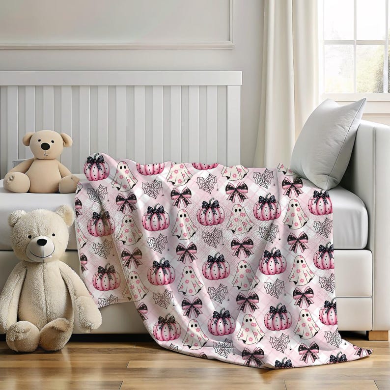 May include: Pink and black Halloween themed throw blanket with a repeating pattern of ghosts, pumpkins, and bows.