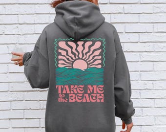 May include: Dark gray hoodie with a graphic on the back featuring a pink sun, teal waves, and the text "TAKE ME to the BEACH" in pink. The hoodie has a hood and long sleeves.