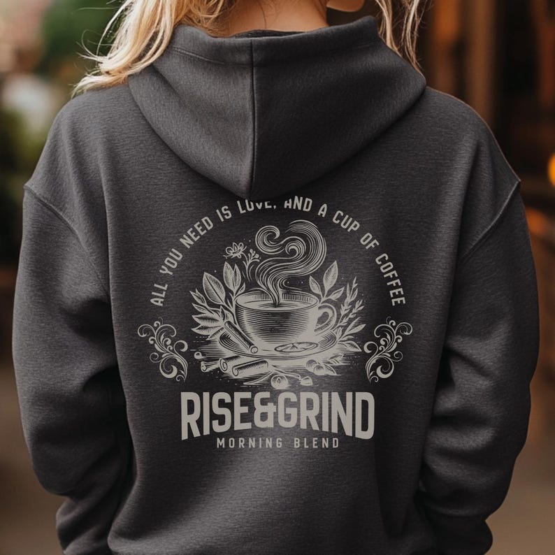 May include: Dark gray hoodie with a coffee-themed graphic on the back. The design includes a coffee cup, steam, and the text "ALL YOU NEED IS LOVE, AND A CUP OF COFFEE" and "RISE&GRIND MORNING BLEND".