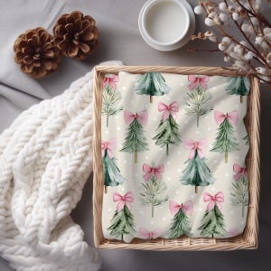 May include: A woven basket contains a cream-colored fabric with a repeating pattern of green Christmas trees adorned with pink bows. The trees are set against a backdrop of white polka dots. The scene is complemented by pine cones and a white knitted blanket.