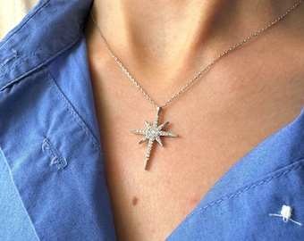 May include: A silver necklace featuring a star-shaped pendant set with clear cubic zirconia stones.
