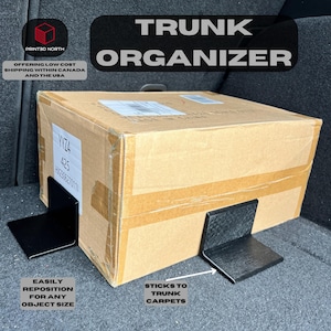 Könnte beinhalten: Schwarzer Kofferraum-Organizer mit zwei verstellbaren Halterungen, die sich an jede Objektgröße anpassen lassen. Der Organizer haftet an Kofferraumteppichen.