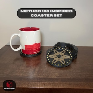 Puede incluir: Un juego de cuatro posavasos negros y dorados con un diseño de banda de rodadura de neumático. Los posavasos están inspirados en el coche Method 106.