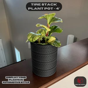 Może przedstawiać: Czarny doniczka do roślin w kształcie stosu opon, o wysokości 10 cm, z zieloną i żółtą rośliną w środku. Doniczka jest zaprojektowana tak, aby wyglądała jak stos opon. Tekst "TIRE STACK PLANT POT - 4" znajduje się w górnej części obrazu. Tekst "DISPLAY YOUR PLANTS IN AUTOMOTIVE STYLE" znajduje się w dolnej części obrazu. Tekst "PRINTED NORTH" znajduje się w małym polu w prawym dolnym rogu obrazu.