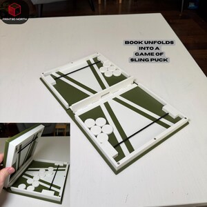 Pode incluir: Um tabuleiro de jogo Sling Puck branco e verde com discos brancos. O tabuleiro é retangular e dobra-se. O texto "BOOK UNFOLDS INTO A GAME OF SLING PUCK" está impresso na imagem.