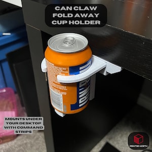 May include: A white 3D printed can holder that folds away. It is mounted under a desk with command strips. The holder is holding a can of orange soda with a white label that says "Original" and "Iron Brew".