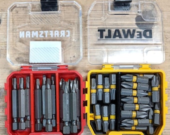 May include: Two clear plastic cases containing sets of screwdriver bits. The case on the left is red and says "CRAFTSMAN" on the lid. The case on the right is yellow and says "DEWALT" on the lid.