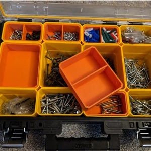 May include: A yellow and black plastic toolbox with multiple compartments filled with various screws, nails, and other hardware. The toolbox has a removable orange tray with two compartments.