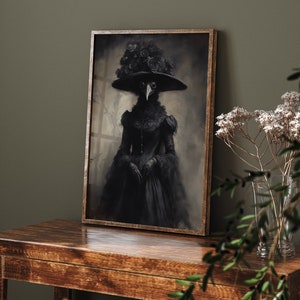 May include: A framed black and white portrait of a figure in a plague doctor costume, wearing a wide-brimmed hat adorned with roses. The artwork is displayed on a dark wooden table, with a vase of white flowers in the background.