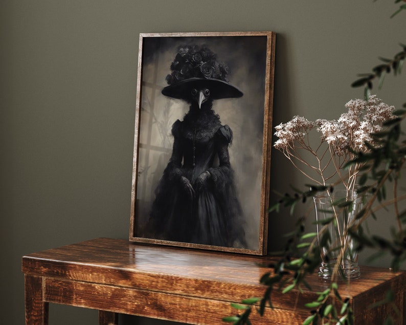 May include: A framed black and white portrait of a figure in a plague doctor costume, wearing a wide-brimmed hat adorned with roses. The artwork is displayed on a dark wooden table, with a vase of white flowers in the background.