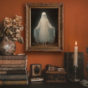 K&ouml;nnte beinhalten: Ein gerahmtes Gem&auml;lde eines Geistes in einem wei&szlig;en Kleid mit Sternenmuster, das an einer Wand mit dunkelorangefarbenem Hintergrund h&auml;ngt. Das Gem&auml;lde ist umgeben von antiken B&uuml;chern, Kerzen und einer kleinen Holzkiste.