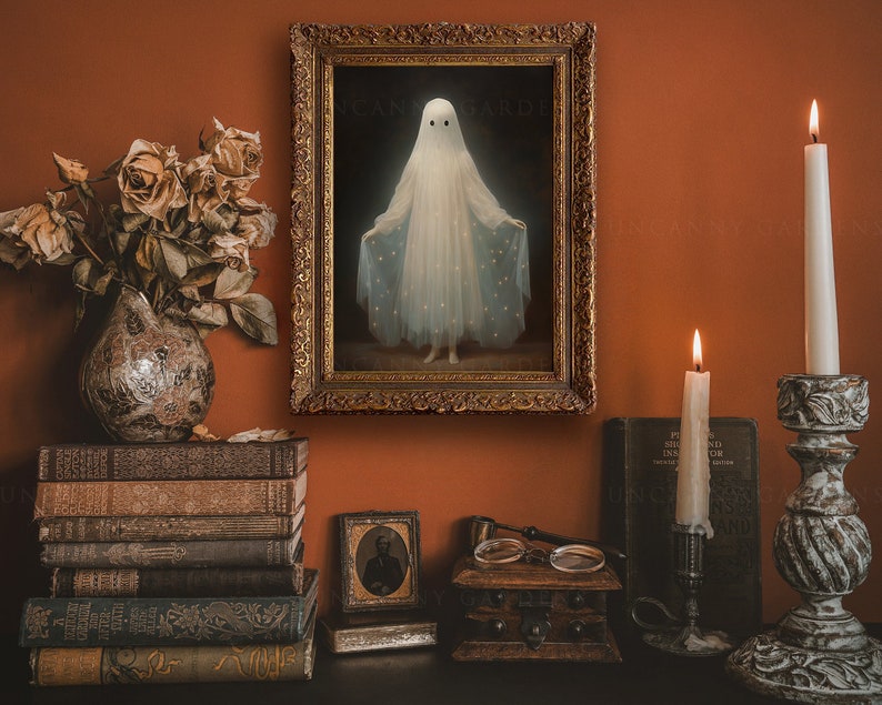 K&ouml;nnte beinhalten: Ein gerahmtes Gem&auml;lde eines Geistes in einem wei&szlig;en Kleid mit Sternenmuster, das an einer Wand mit dunkelorangefarbenem Hintergrund h&auml;ngt. Das Gem&auml;lde ist umgeben von antiken B&uuml;chern, Kerzen und einer kleinen Holzkiste.