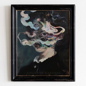May include: A framed surrealist portrait with a dark background. The artwork features a figure with multiple eyes and swirling, cloud-like forms. The frame is black, and the text "UNCANNY GARDENS" is visible.
