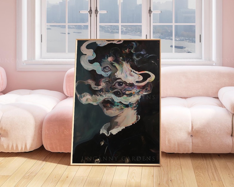 May include: A framed artwork featuring a surreal portrait with multiple eyes and swirling, smoky forms. The subject wears a dark outfit with a white collar. The text "UNCANNY GARDENS" is visible at the bottom of the artwork.
