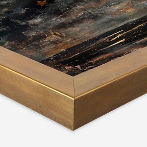 May include: Close-up of the corner of a gold-toned picture frame. The frame is made of wood and has a smooth, polished finish.